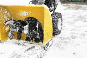a yellow snow plow sitting on top of snow covered ground.